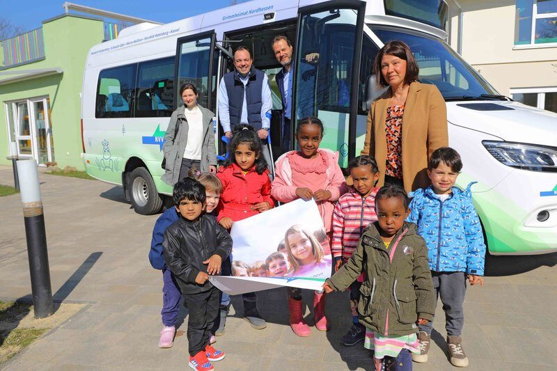 Kindergruppe mit Erwachsenen vor NVV-Bus