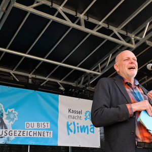 Christof Nolda auf der Bühne, im Hintergrund das blaue Banner des Klimaschutzpreises mit dem Schriftzug: Du bist aufgezeichnet!
