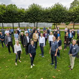 Mitglieder des Klimaschutzrats und der Themenwerkstätten stehen auf einer Grasfläche vor Bäumen im Botanischen Garten der Stadt Kassel.