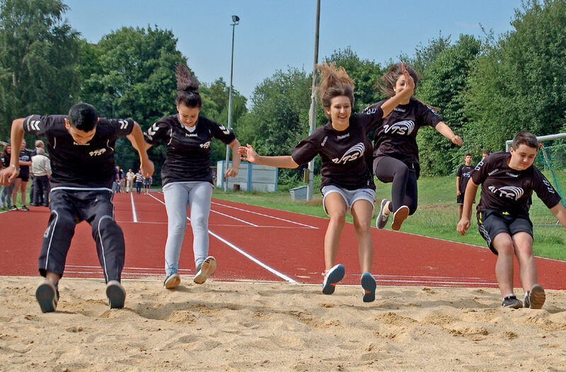Jugendliche springen in Sandfläche