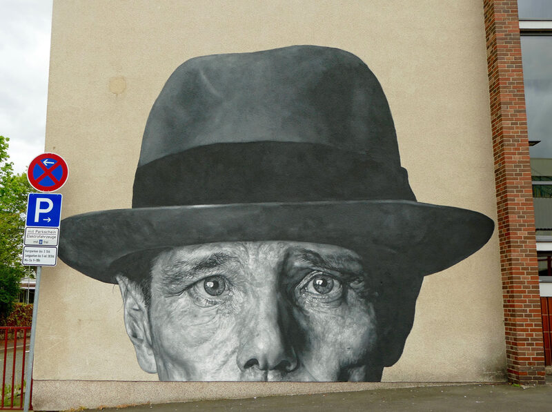 as Wandgemälde zeigt das Gesicht von Joseph Beuys oberhalb des Mundes. Wie immer: mit Hut