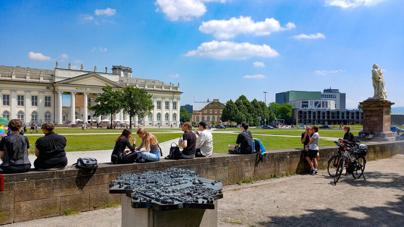 Friedrichsplatz mit Menschen.  Vorne im Bild das Modell der zerstörten Stadt