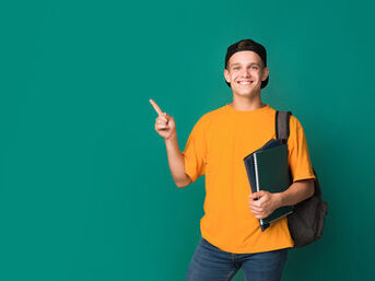 Teen student with books pointing on copy space