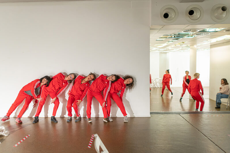 Tänzerinnen in roten Jogging Anzügen vor einer weißen Wand und im Spiegel