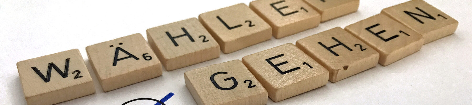 Mit Buchstaben-Plättchen eines Scrabble-Spiels gelegte Worte Wählen gehen mit Kreuz in einem Feld