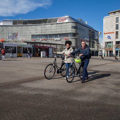 Zwei Fahrradfahrer, die auf dem Königsplatz in Kassel ihre Fahrräder schieben