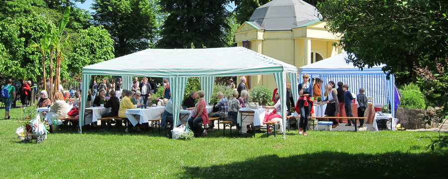 Gartenpavillon mit Menschen, die an Tischen und Bänken sitzen