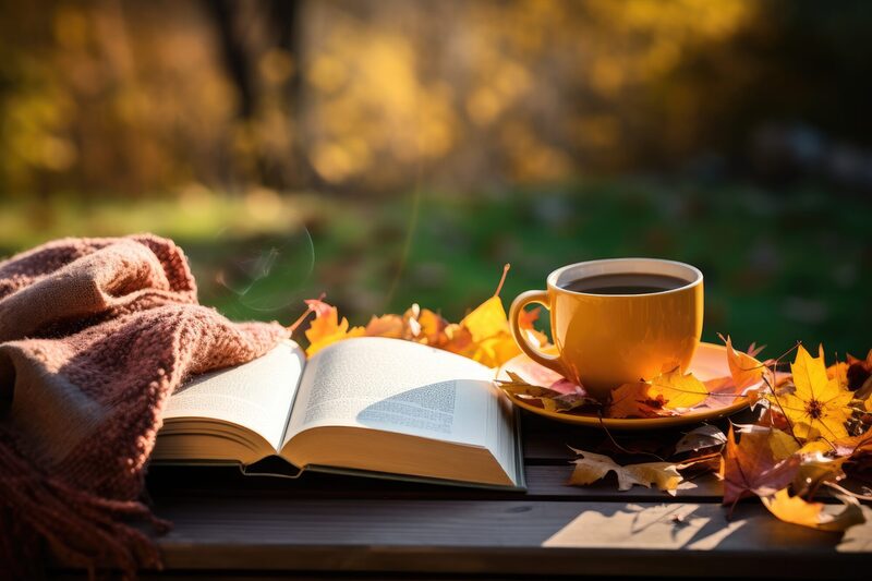 Tasse mit schwarzem Tee, Buch und Herbstblätter; KI-generiertes Bild