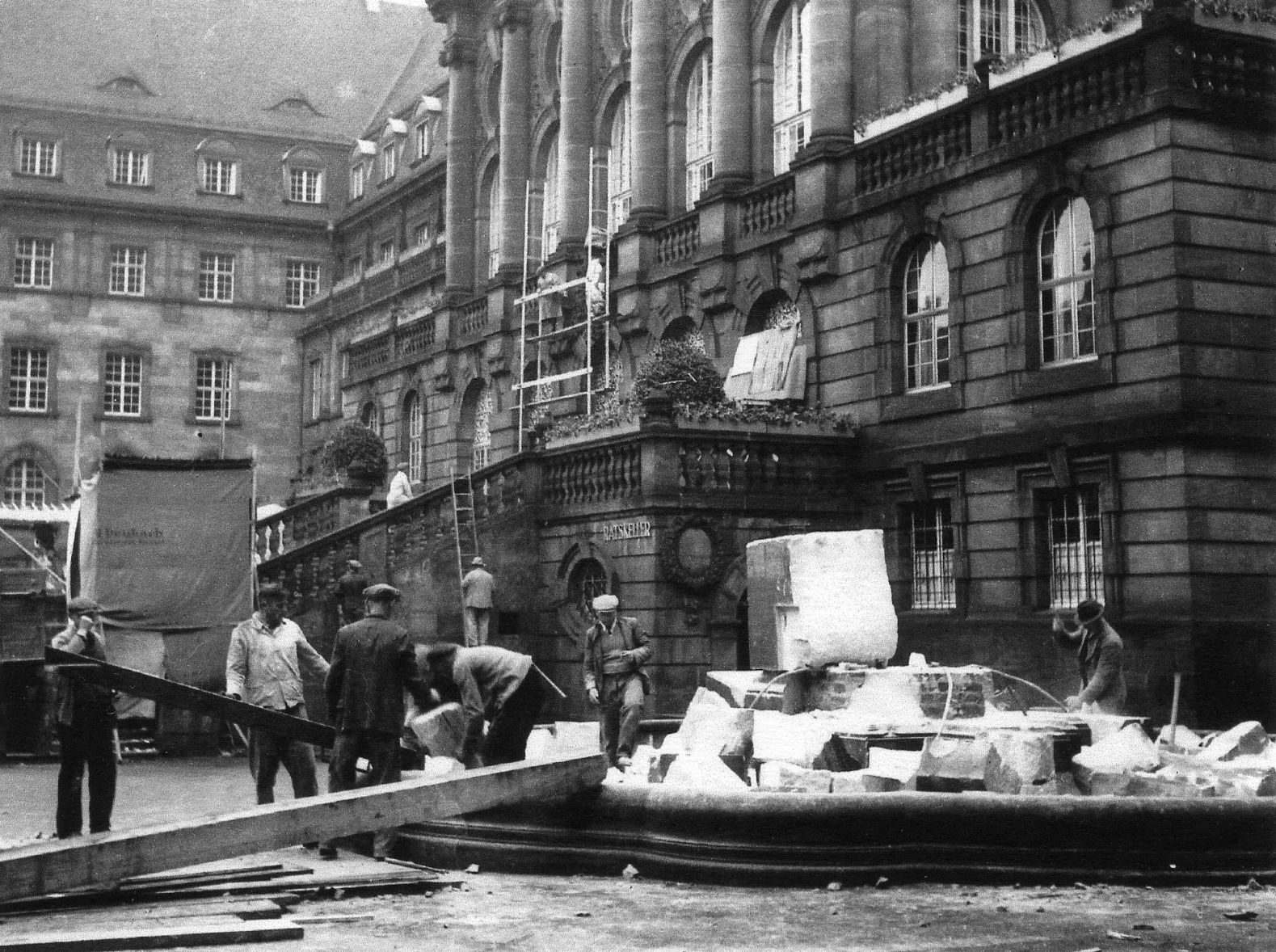 Arbeiter tragen Reste des von den Nazis zerstörten Brunnens ab
