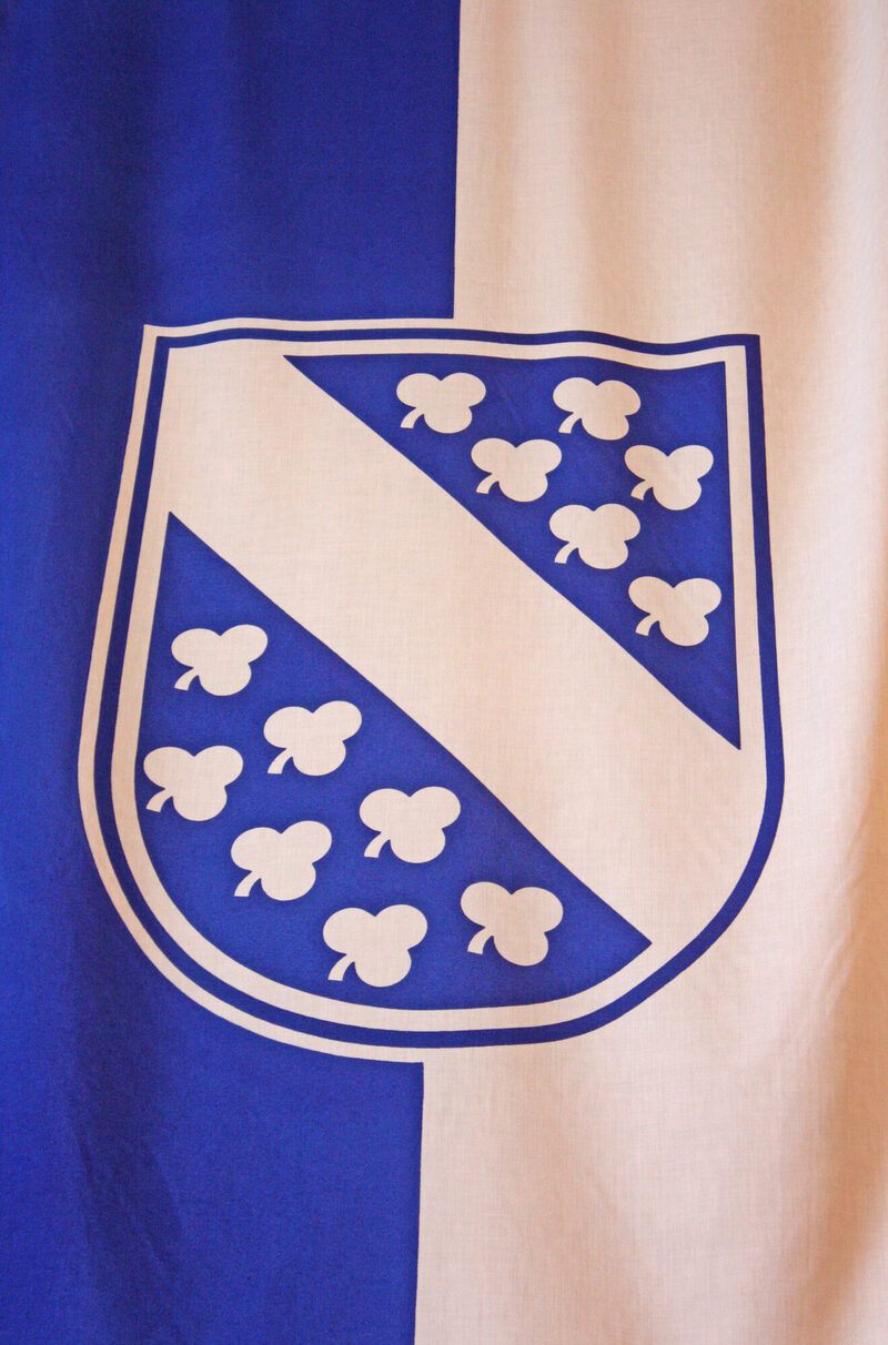 Wappen mit 13 Kleeblättern auf der blau-weißen Fahne