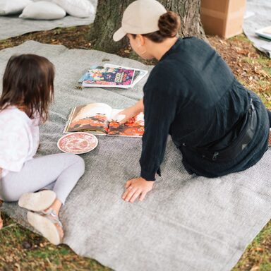 Frau und Kind von hinten aufgenommen auf einer Decke im Park
