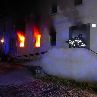 Feuerwehrleute beim Einsatz an brennendem Gebäude