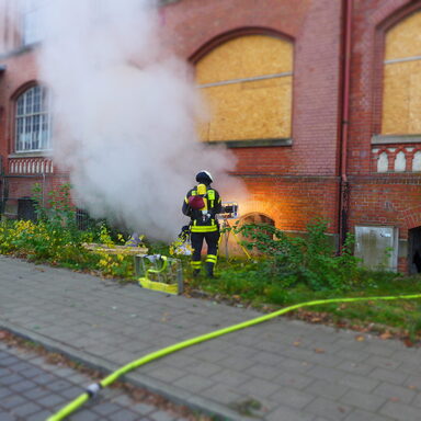 Feuerwehrmann löscht Feuer an Gebäude
