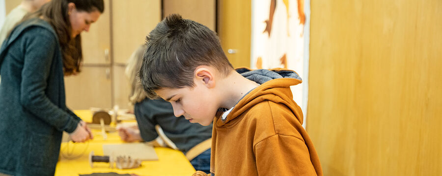 Ein Junge siebt selbstgemahlene Körner beim Workshop Steinzeitbäcker.