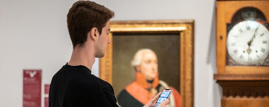 Ein Besucher richtet sein Handy auf ein Objekt in der Ausstellung des Museums