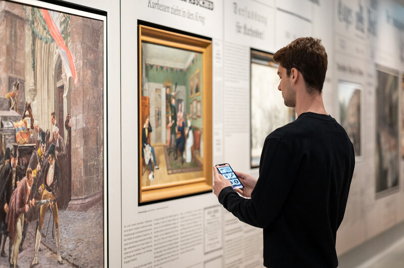 Ein Besucher richtet sein Handy auf ein Objekt in der Ausstellung des Museums