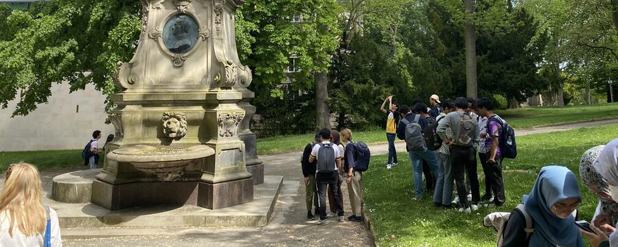 Junge Menschen stehen im Murhardpark vor einem Denkmal