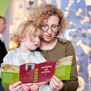 Ein Kind und seine Mutter lesen in der Broschüre vom Stadtmuseum