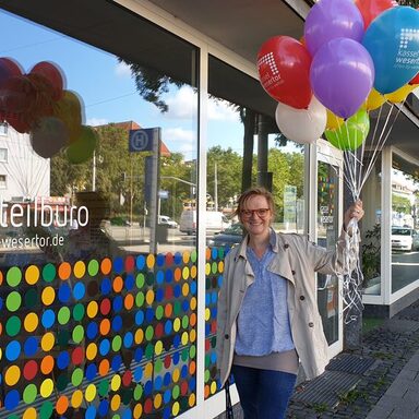 Frau mit Luftballons vor dem Stadtteilbüro