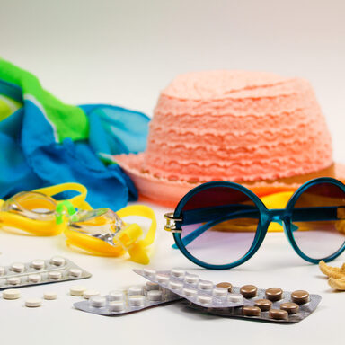 Tabletten, Schwimmbrille, Sonnenbrille und Sonnenhut für die Reise