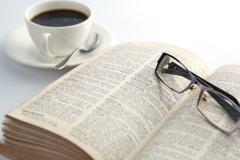Geöffnetes Buch mit Kaffetasse und Brille