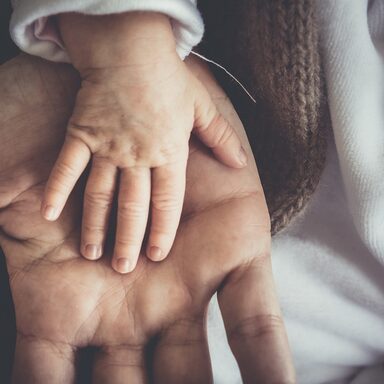 Die Hand eines Neugeborenen liegt auf einer Hand