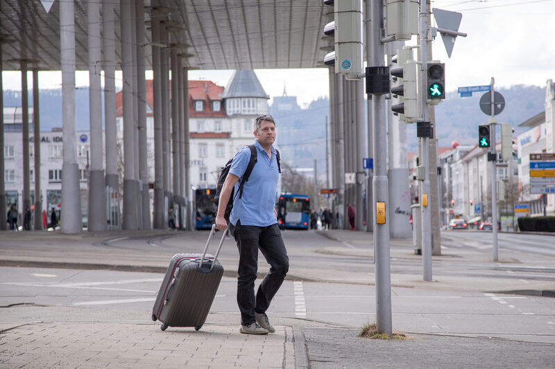 Mann mit Koffer vor Bahnhof Kassel Wilhelmshöhe
