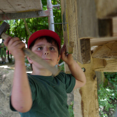 Foto von Junge, der einen Nagel ins Holz hämmert