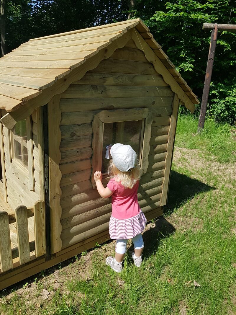 Ein kleines Mädchen steht vor einer Holzhütte